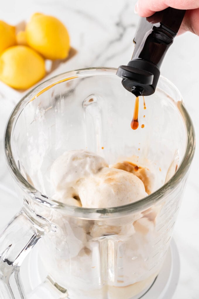 pouring vanilla extract in a blender to make frosted lemonade