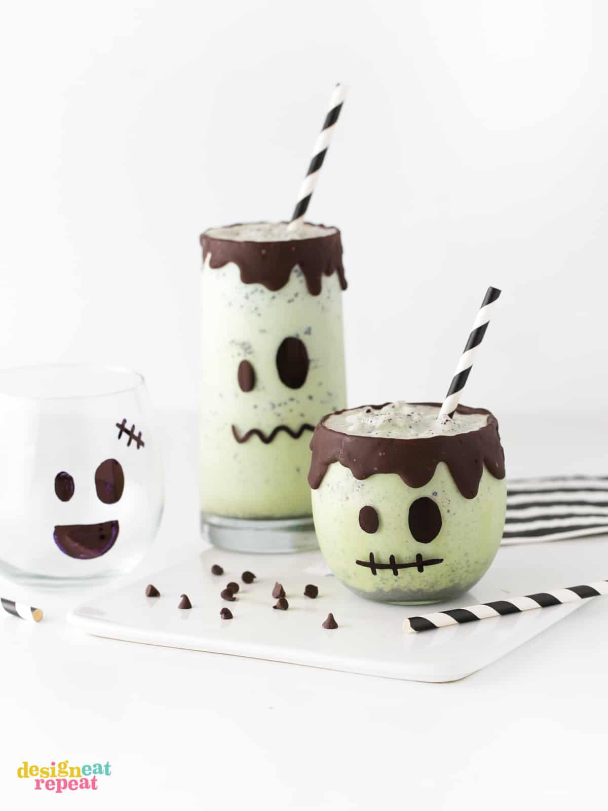 Mint chip green Halloween milkshakes decorated like Frankenstein with chocolate drip rim and striped black paper straws