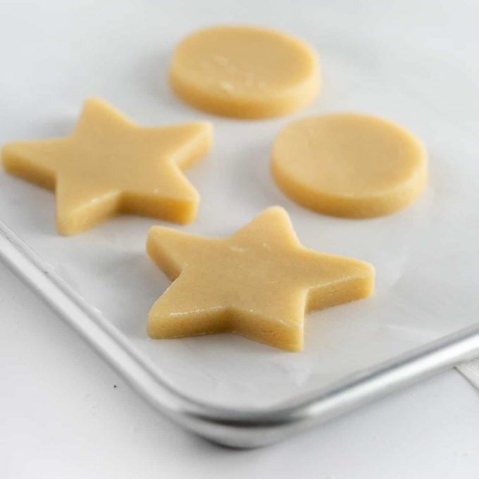 Cut out star and circle shaped cookie dough on baking tray