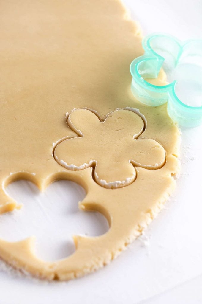 Sugar cookie dough being cut with flower cookie cutter