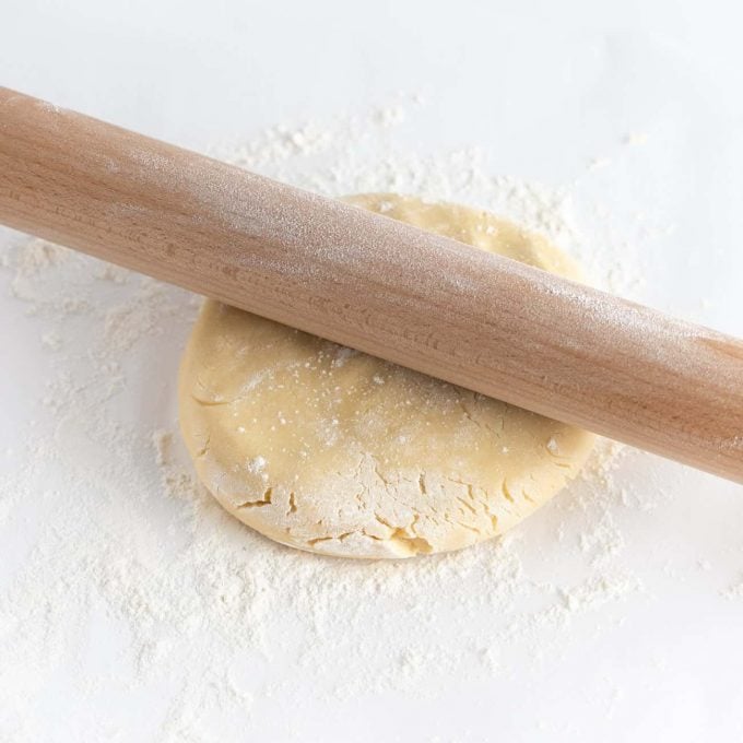 Wooden rolling pin rolling out ball of sugar cookie dough