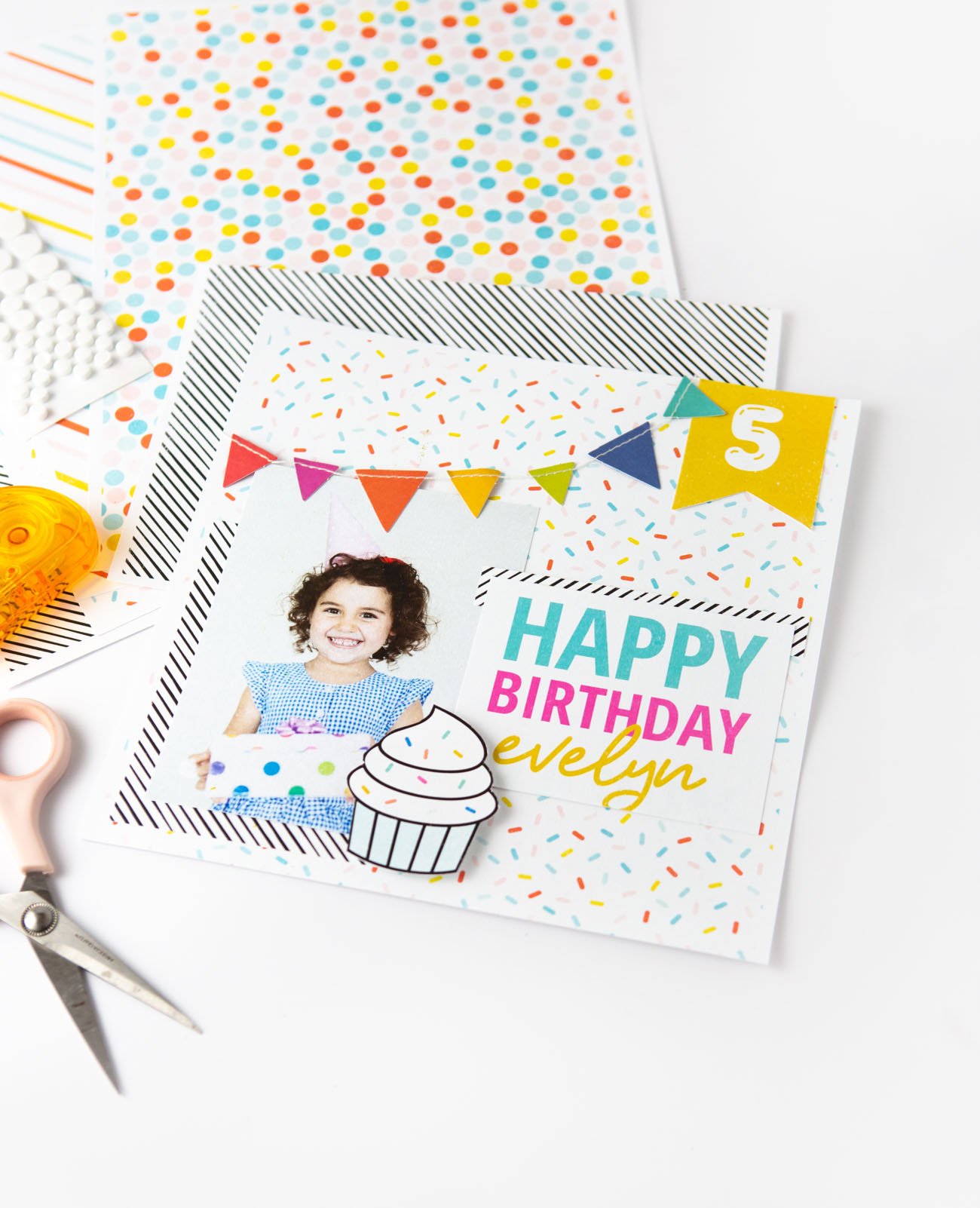 Colorful rainbow scrapbook page design with Happy Birthday text, cupcake, and banner