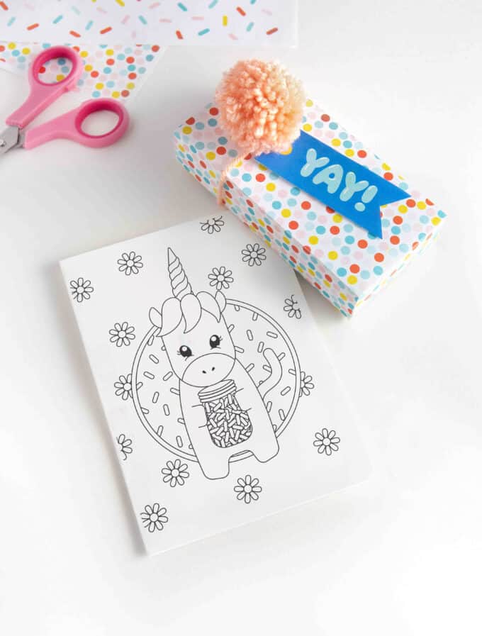 Printed 5x7 unicorn birthday card with colorful gift box with blue "YAY" gift tag and pink pom pom.  