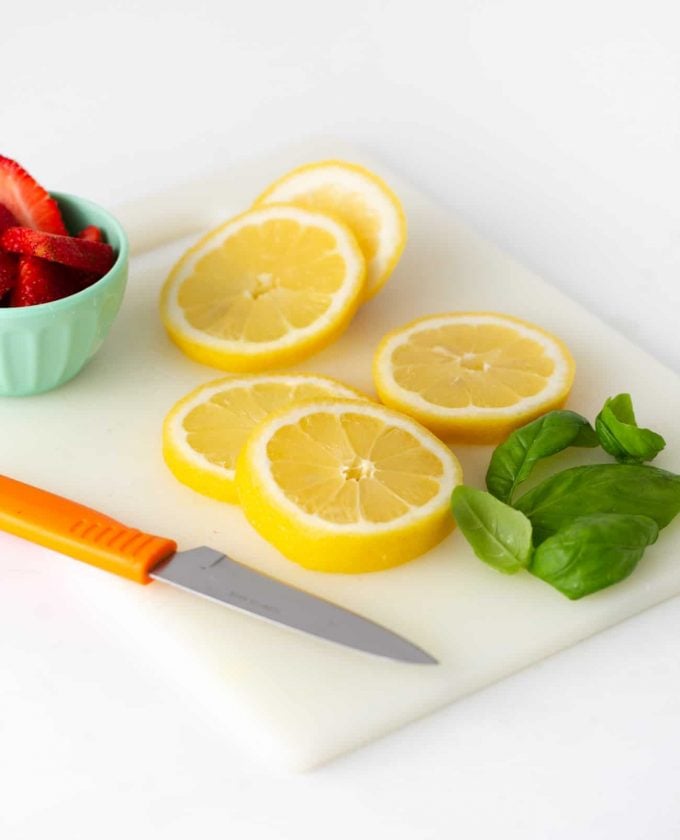 Lemon slices on cutting board with strawberries and basil