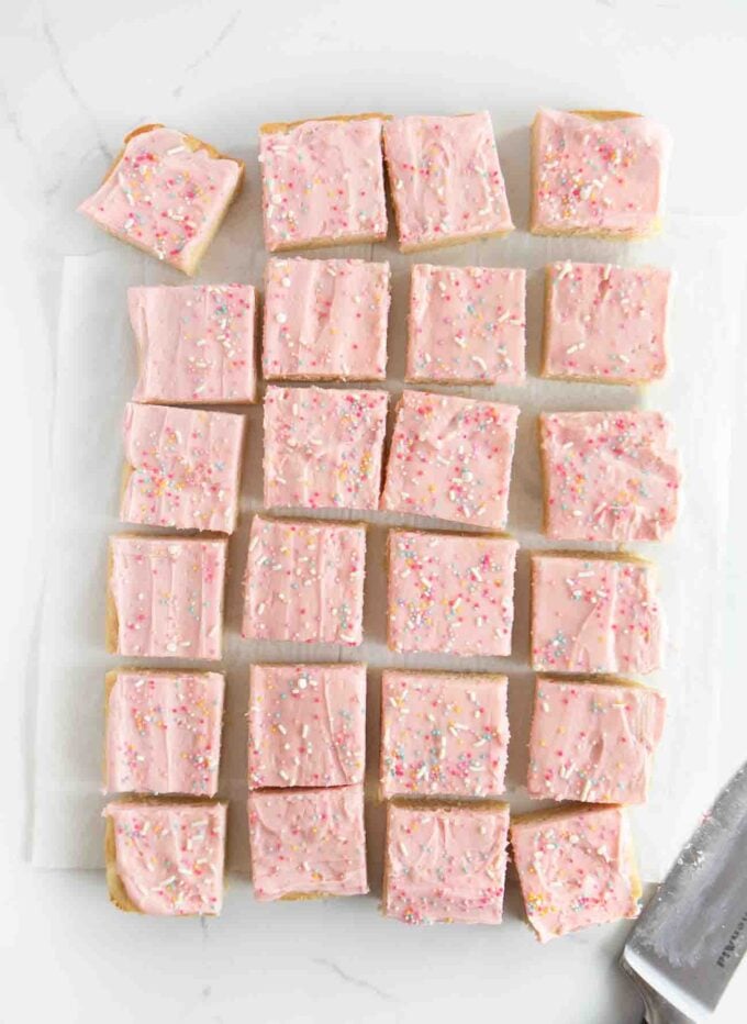 pan of cut sugar cookie bars with pink frosting and sprinkles